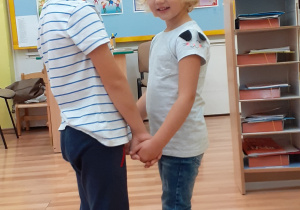 Chłopczyk i dziewczynka stoją w parze i trzymają się za rączki.